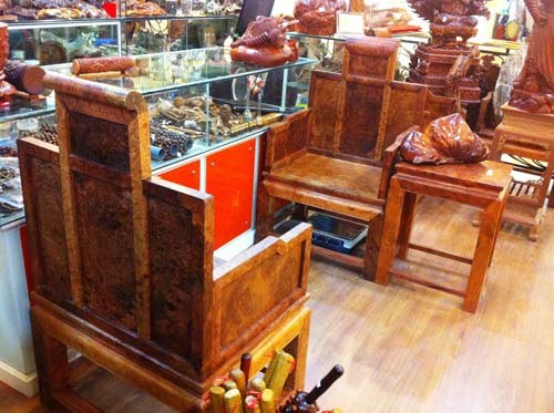 Một đôi ghế kèm chiếc bàn nhỏ kế bên được làm bằng gỗ nu hương nổi tiếng của cơ sở Thắng Trinh ở tầng 6 Tràng Tiền Plaza có giá 180 triệu đồng.